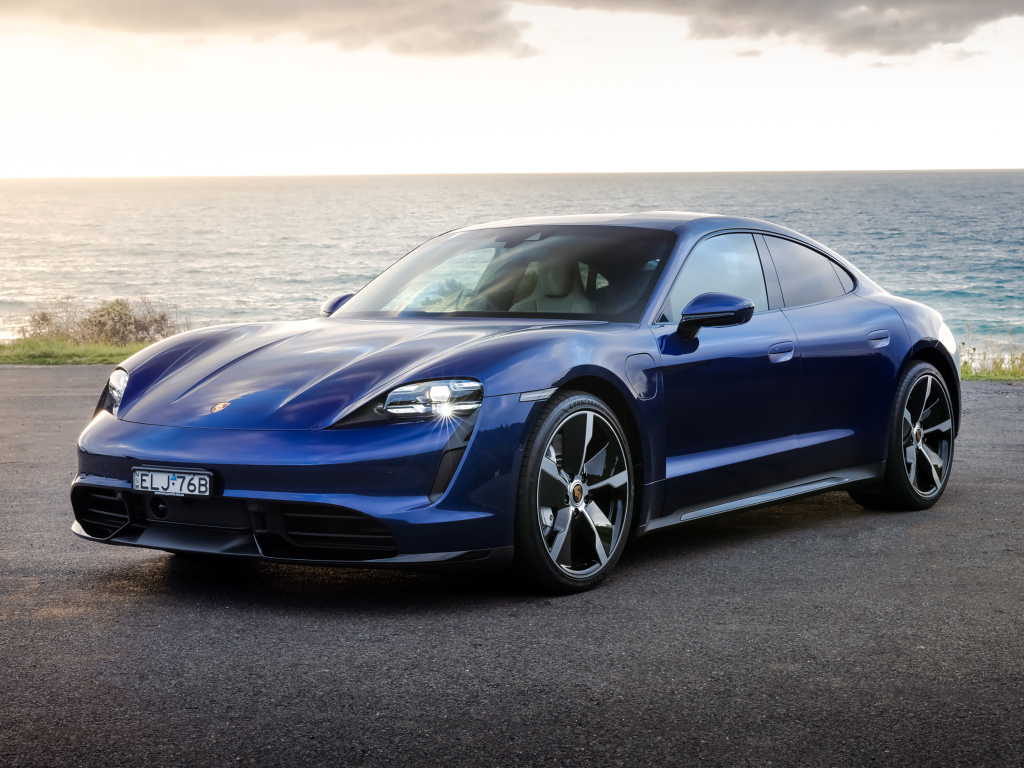 Синий автомобиль Porsche Taycan Turbo у моря