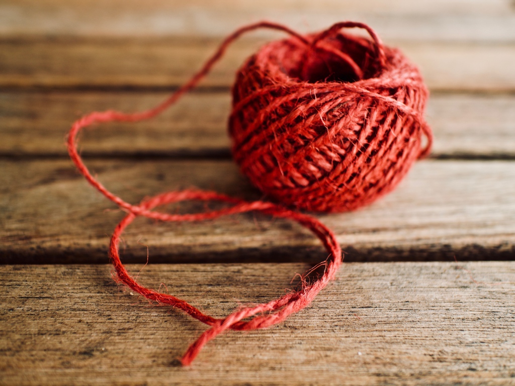 Клубок красной пряжи на деревянном столе 