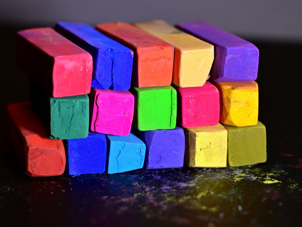 Разноцветные мелки для школы на черной поверхности 