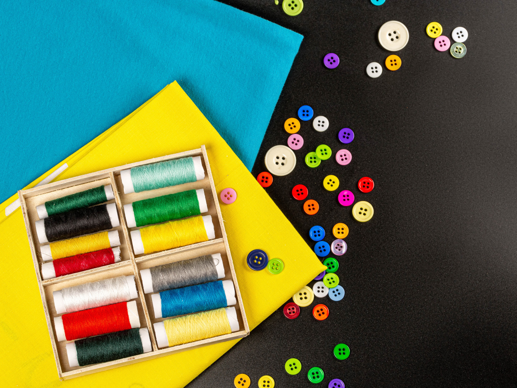 Разноцветные нитки, пуговицы и бумага на черном фоне 