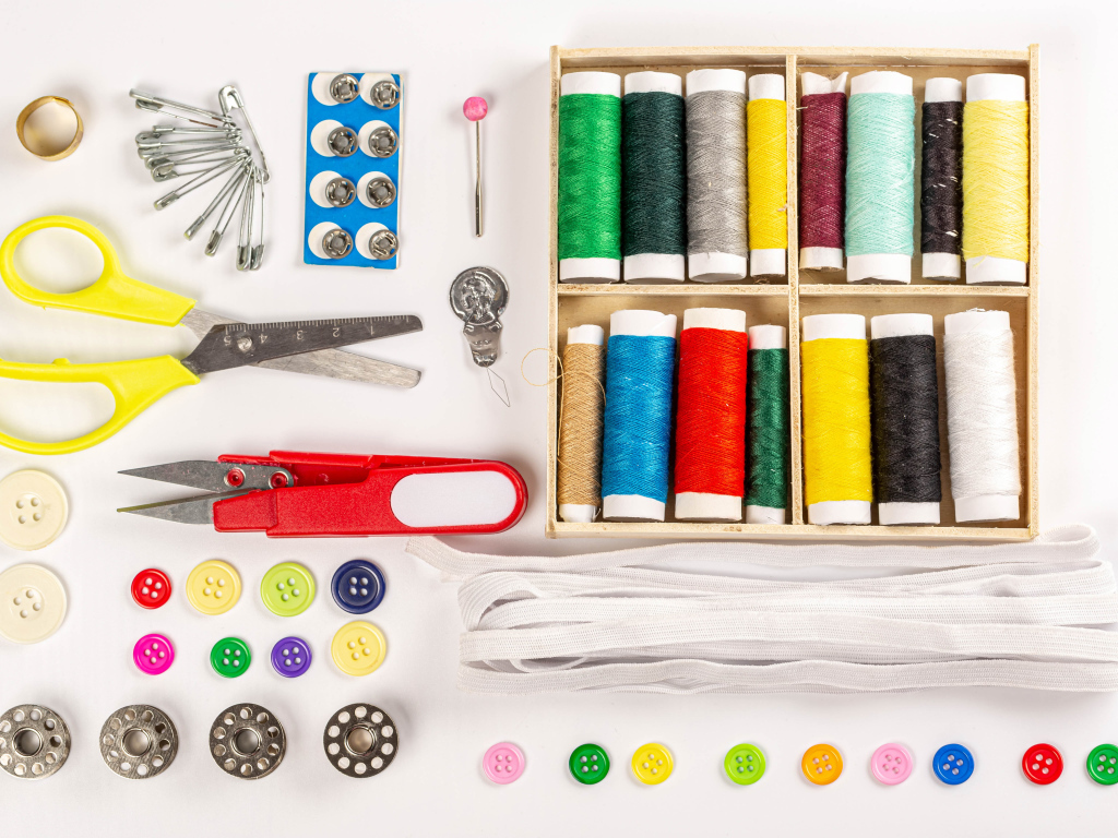 Разноцветые нитки и предметы для шитья на белом фоне 