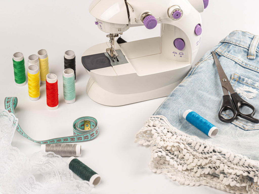 Швейная машинка,юбка и нитки на белом фоне 