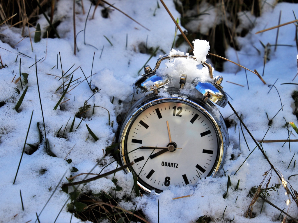 Серебряный будильник лежит в снегу