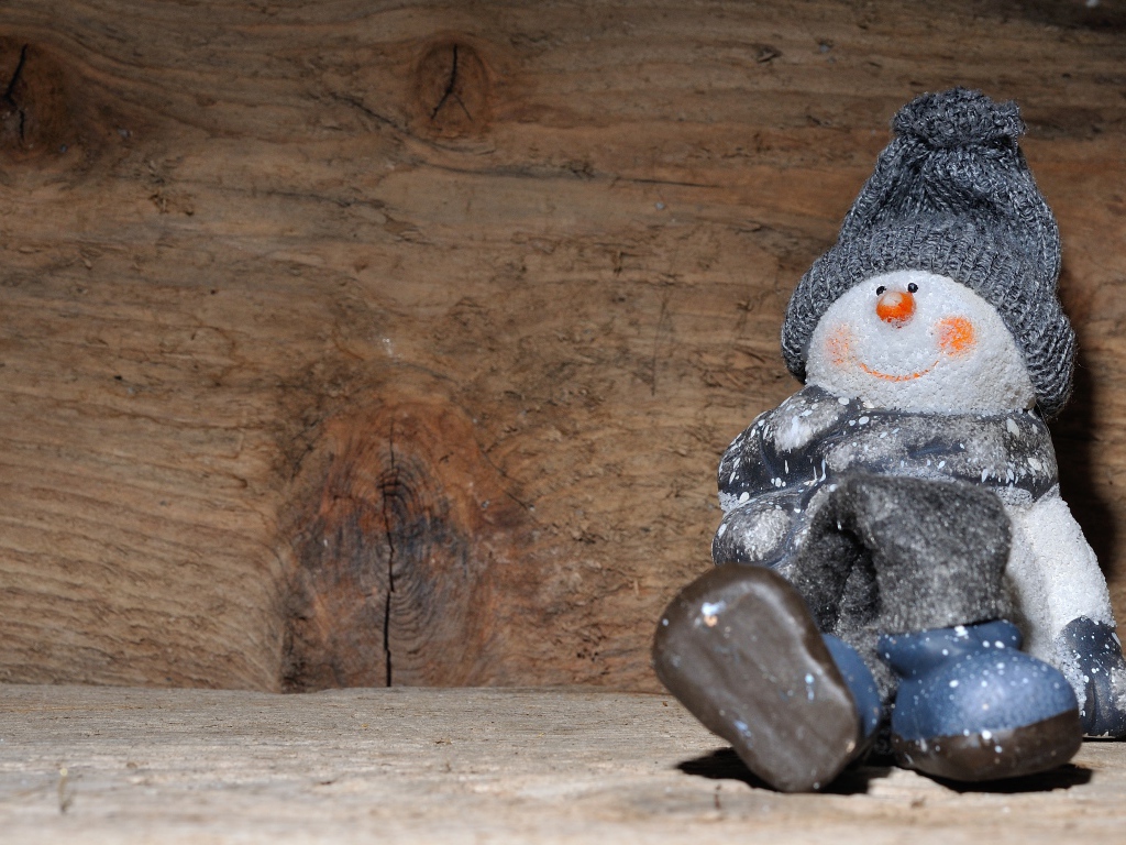 Фигурка снеговик у деревянной стены
