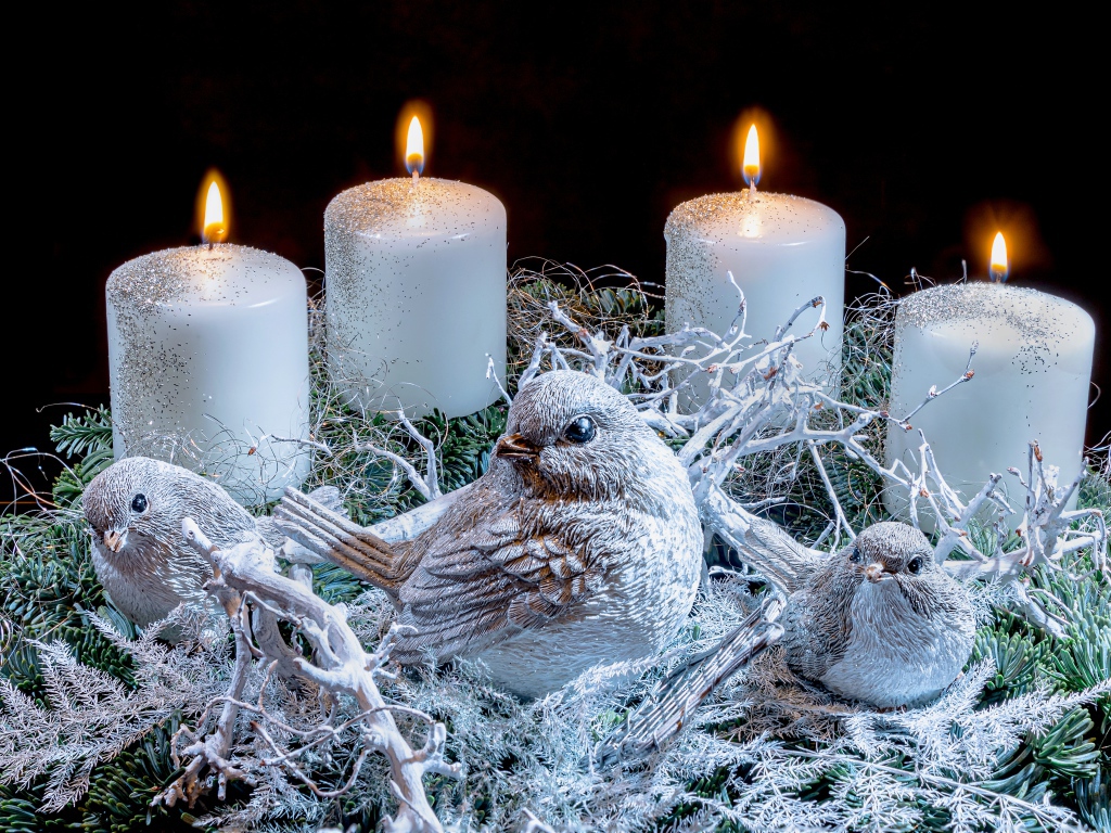 Три зажженные свечи со статуэтками птицами 