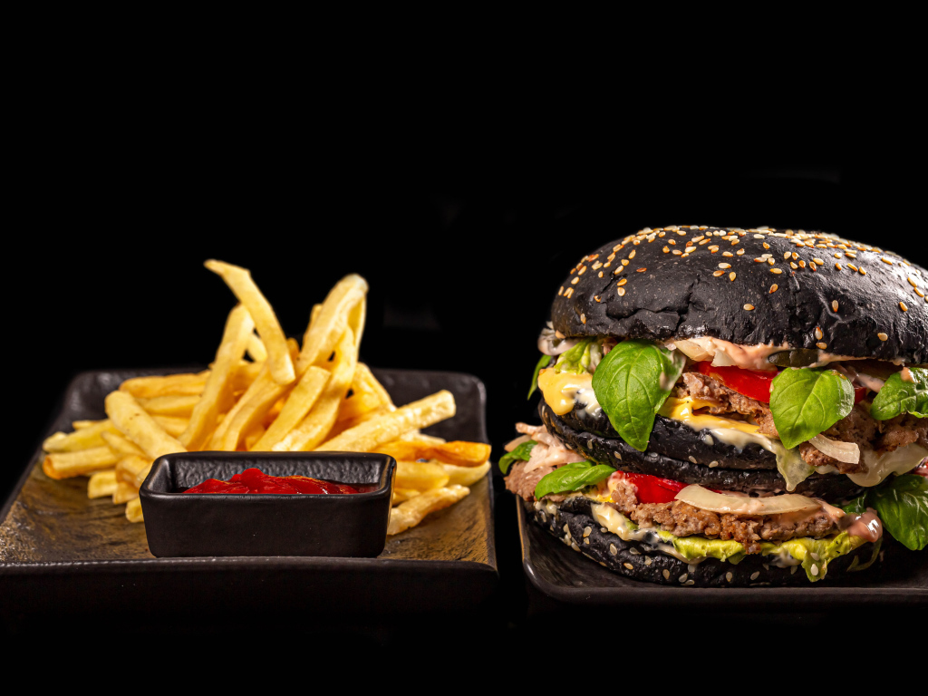 Большой черный гамбургер с картофелем фри и кетчупом 