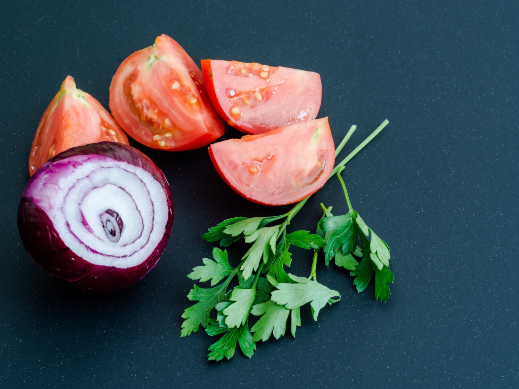Лук, помидоры и петрушка на сером столе