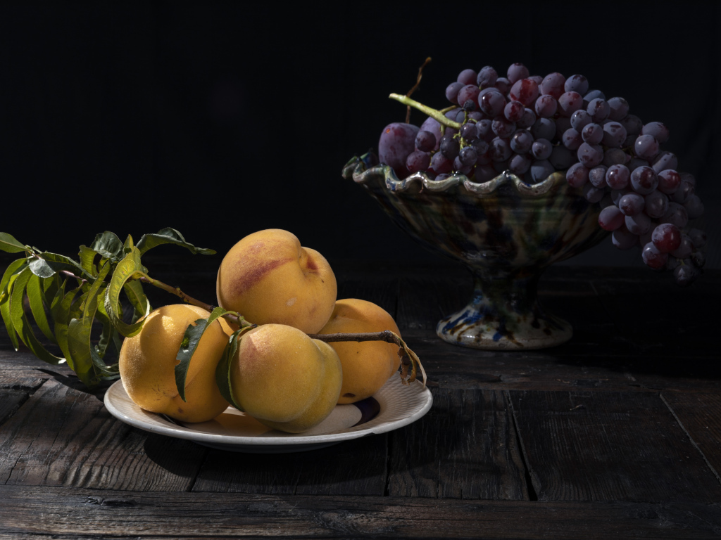 Красивые сочные персики на столе с виноградом