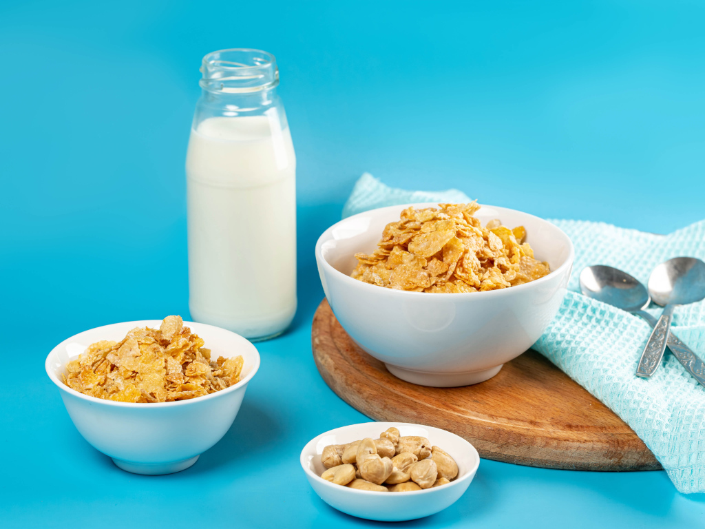 Хлопья на столе с орехами и молоком на голубом фоне