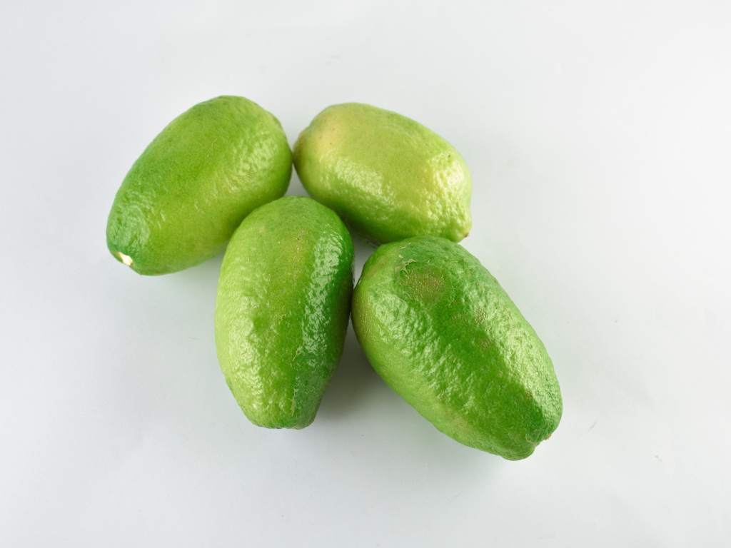 Четыре зеленых лимона на белом фоне