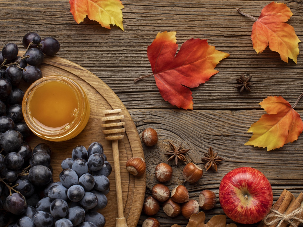 Мед на столе с виноградом, орехами и яблоками