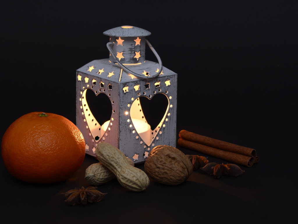 Мандарин, орехи, специи и фонарь на черном фоне