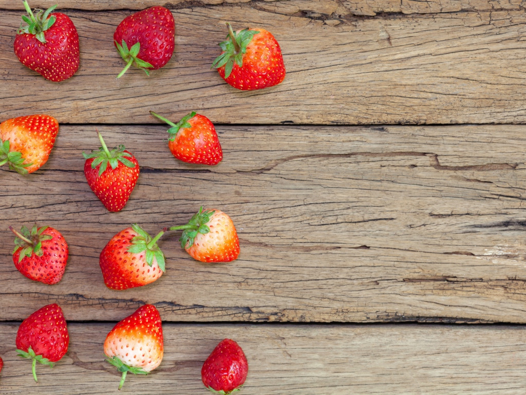 Спелая красная клубника лежит на деревянном столе