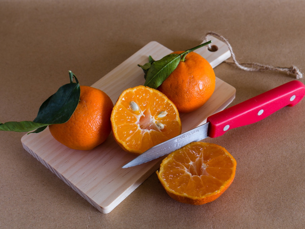 Мандарины лежат на доске с ножом 