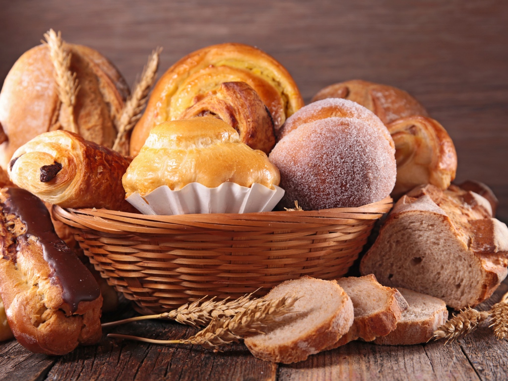 Свежая аппетитная выпечка в корзине на столе 