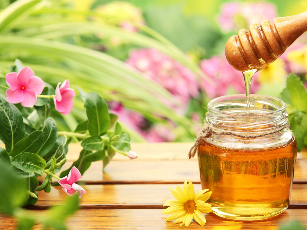Банка ароматного меда на столе с цветами