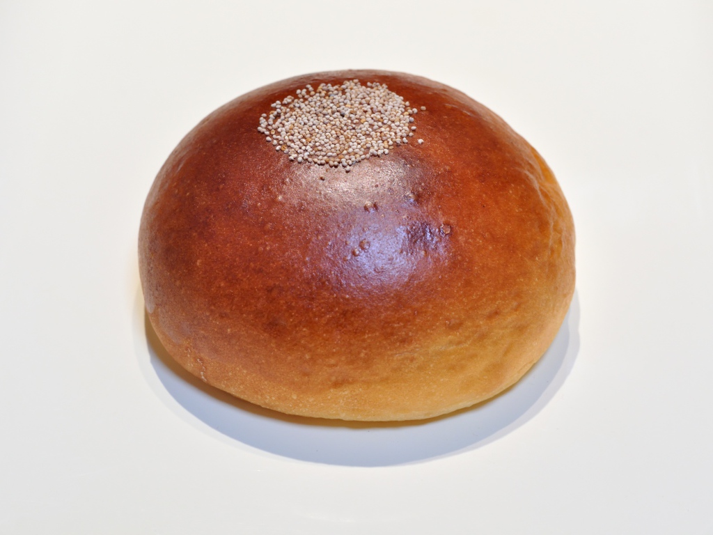 Аппетитная круглая булочка на сером фоне