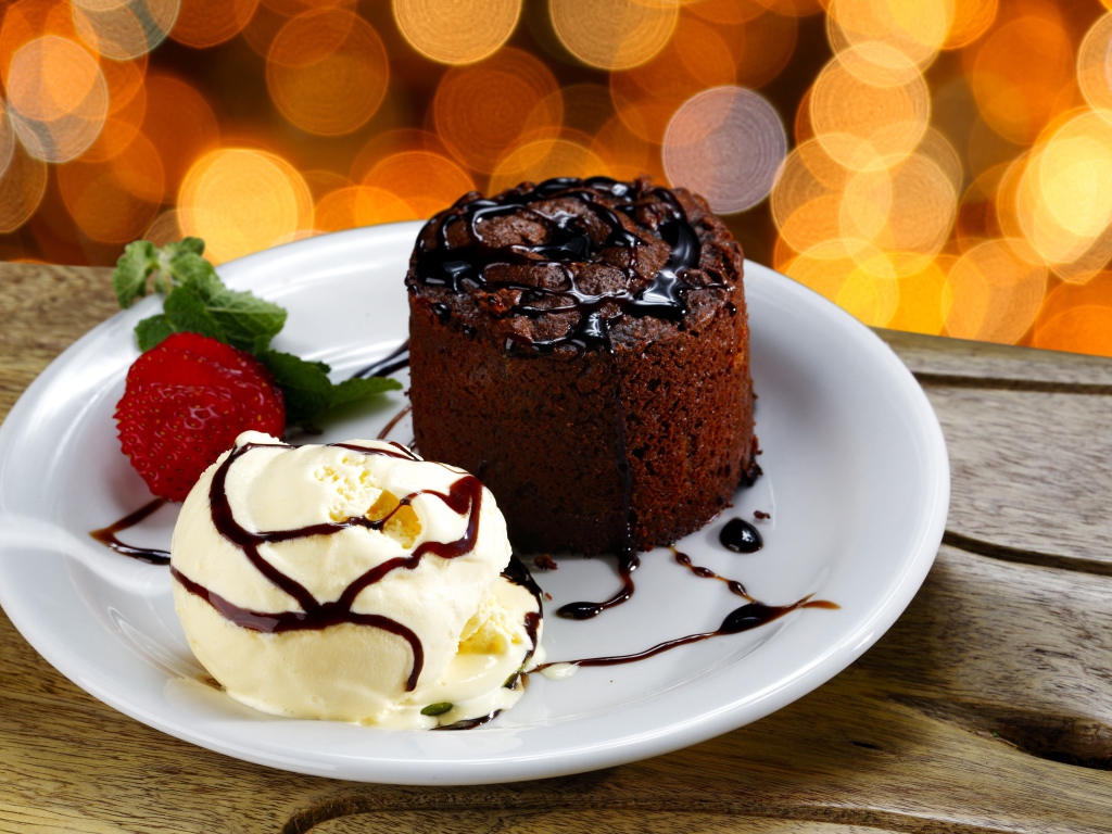 Шоколадный десерт с мороженым и клубникой на белой тарелке 