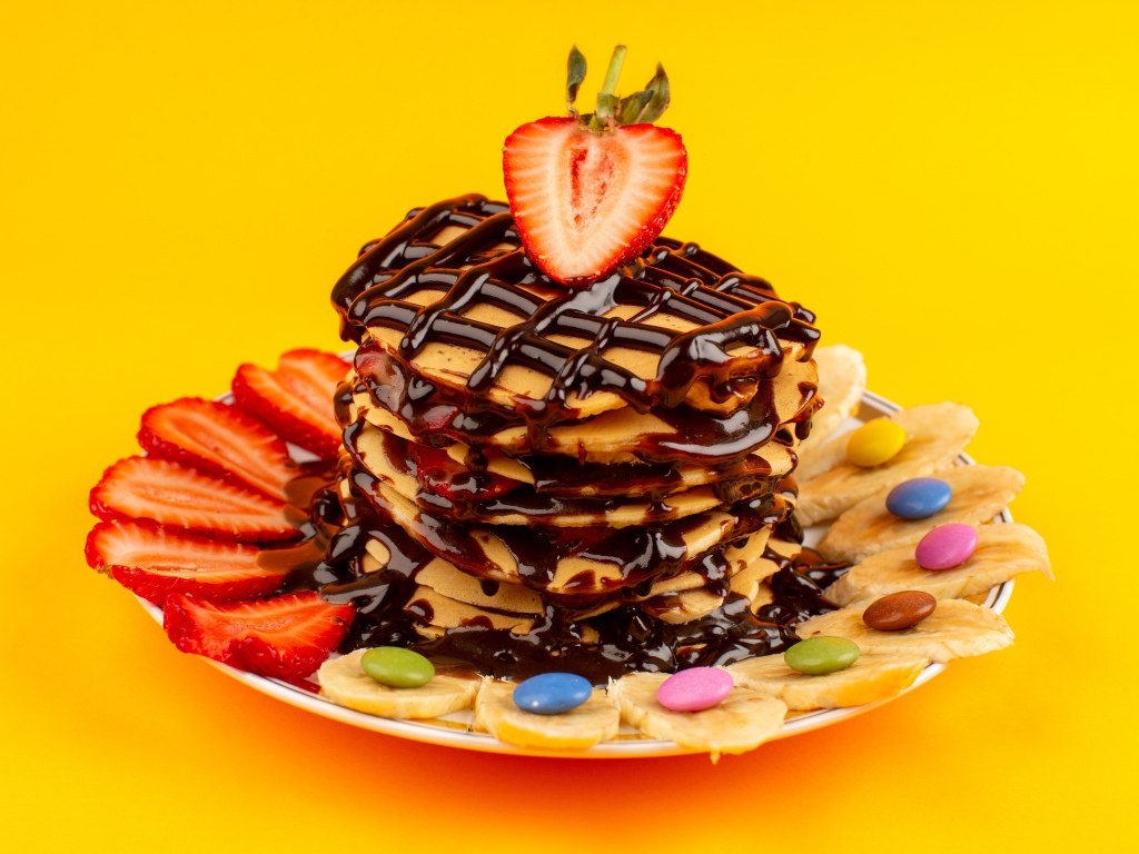 Оладьи с шоколадом, клубникой и бананом на желтом фоне 