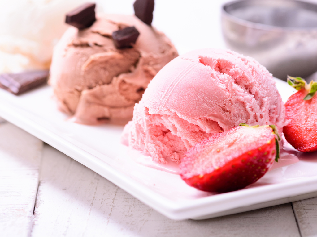Шарики мороженого на большой белой тарелке с клубникой