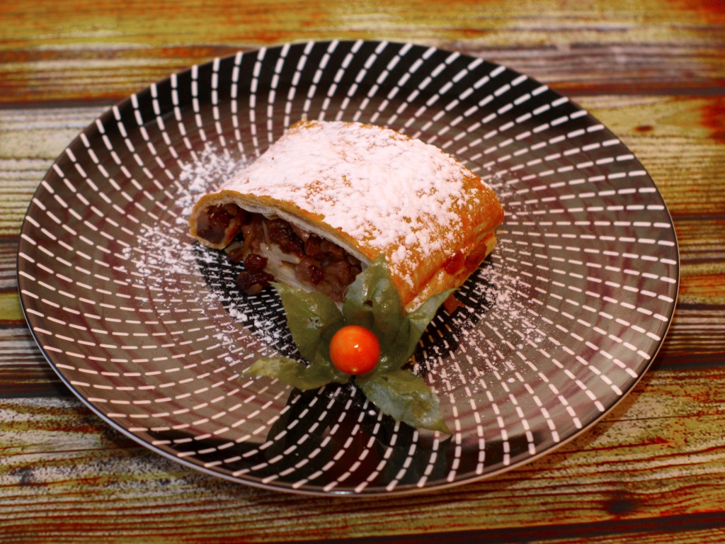 Кусок яблочного штруделя на тарелке 