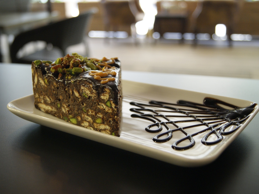 Кусок торта с фисташками на белой тарелке 