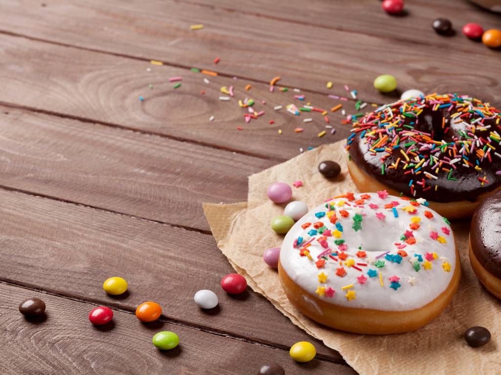 Сладкие пончики с глазурью на столе с конфетами