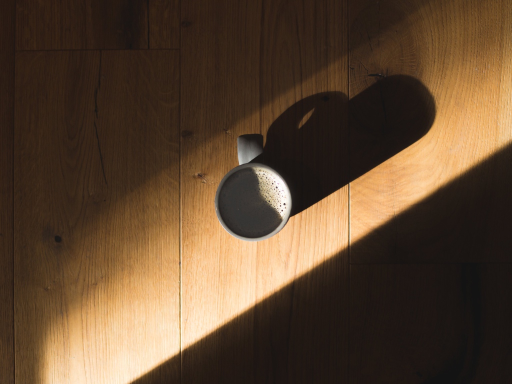 Чашка кофе стоит на столе в лучах солнца