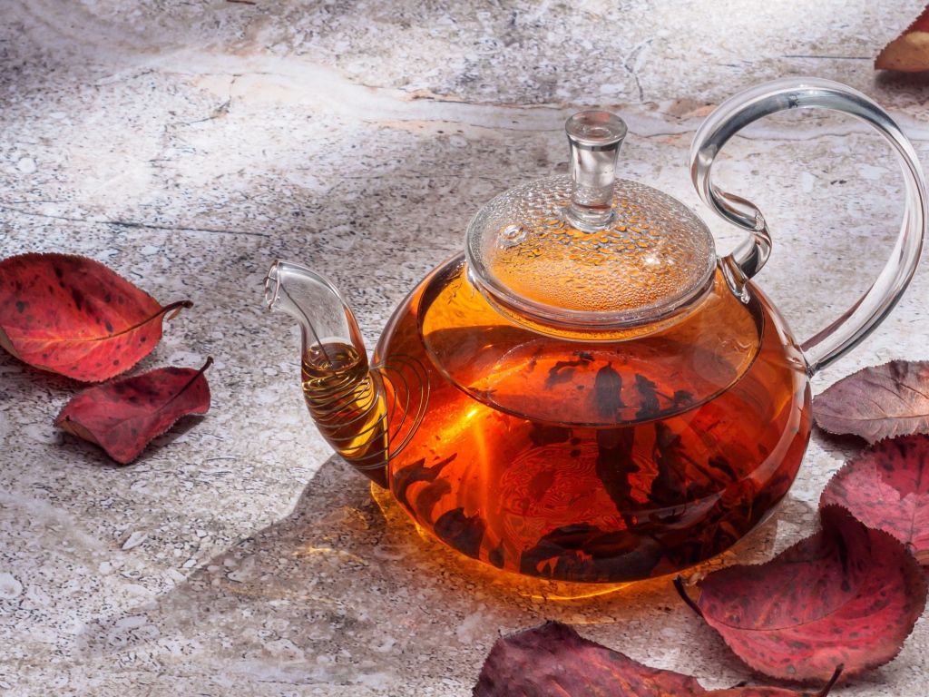 Стеклянный чайник на столе с листьями