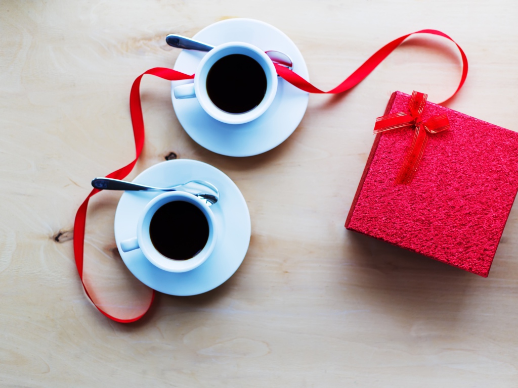 Две чашки кофе на столе с подарком