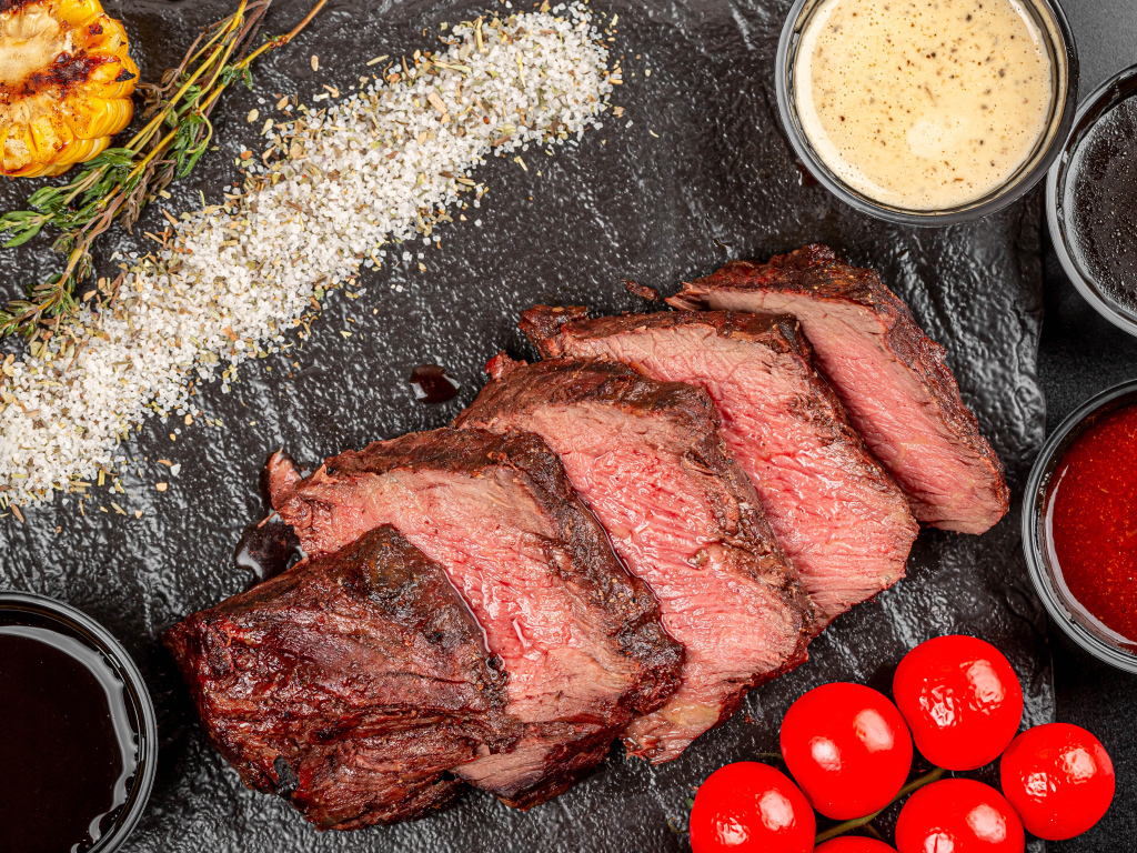 Мясо с помидорами и соусами на доске 