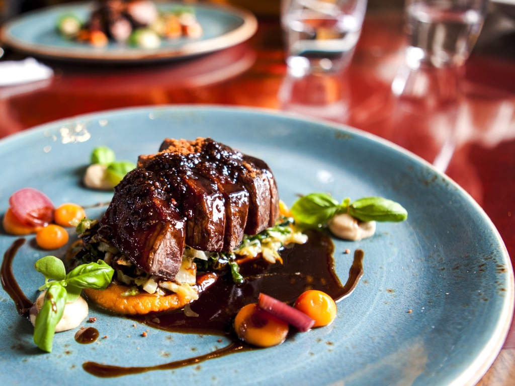 Кусок мяса с соусом на тарелке в ресторане