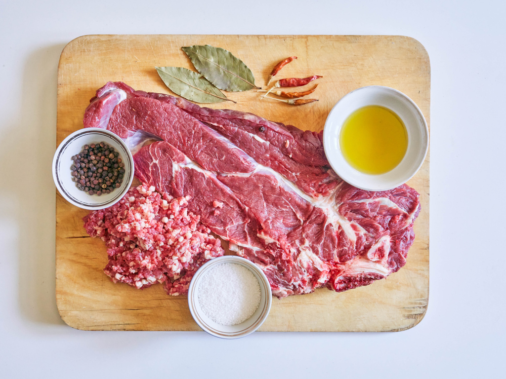 Кусок мяса со специями и оливковым маслом на доске 