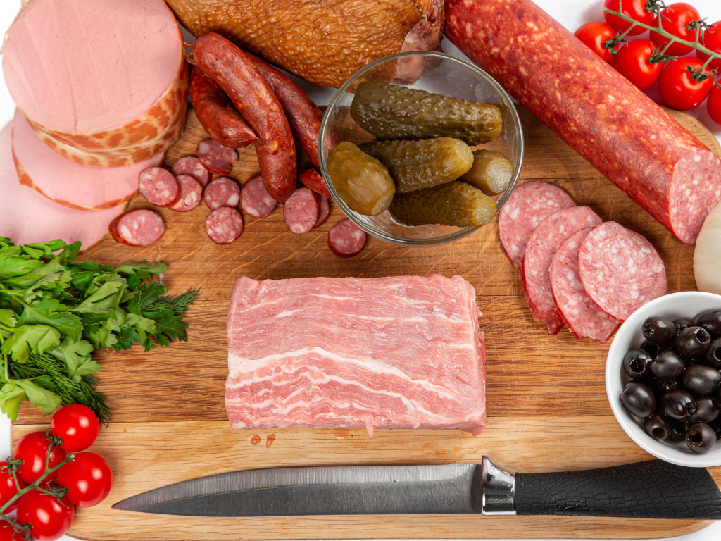 Sausage on the table with cucumbers, tomatoes and herbs