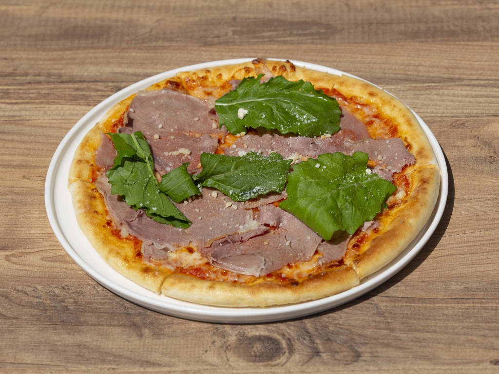 Пицца с кусочками мяса и зеленью на столе