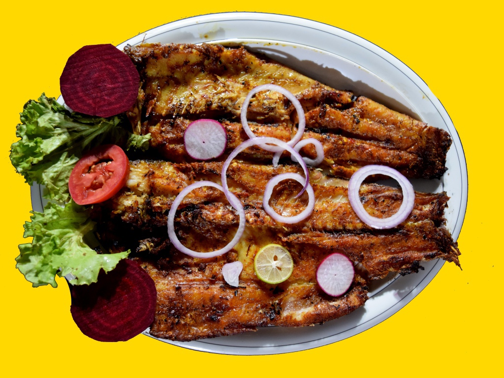 Жареная рыба с листьями салата, помидорами и свеклой на желтом фоне