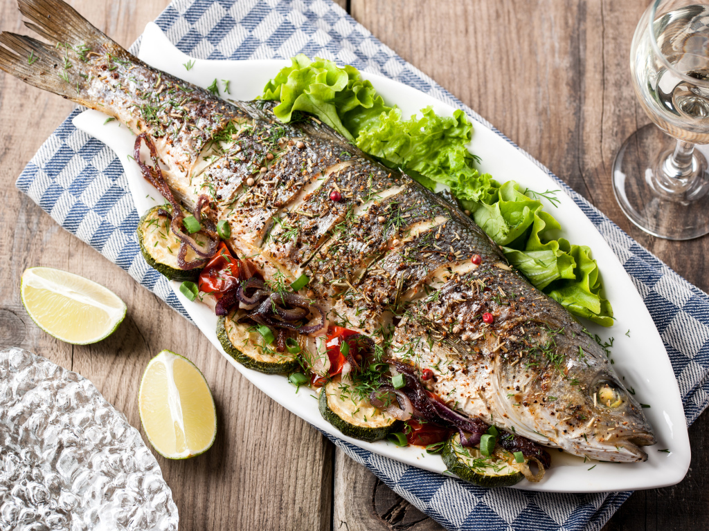 Большая запеченная рыба с кабачками и листьями салата