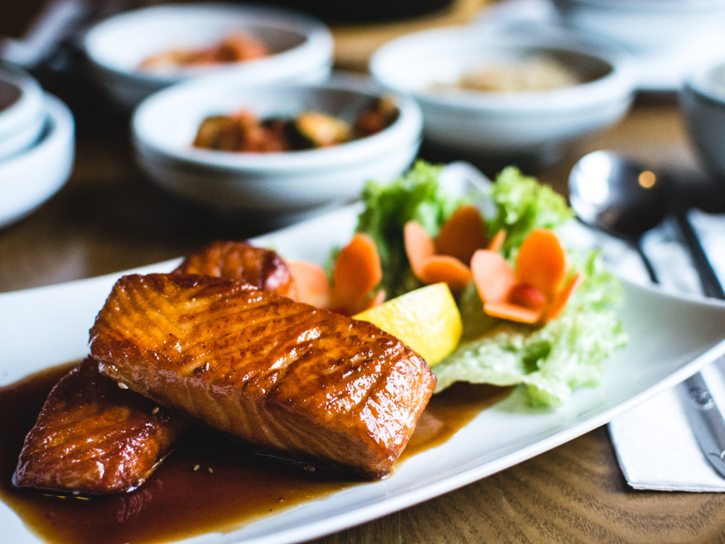 Два куска рыбы в соусе с овощами на тарелке