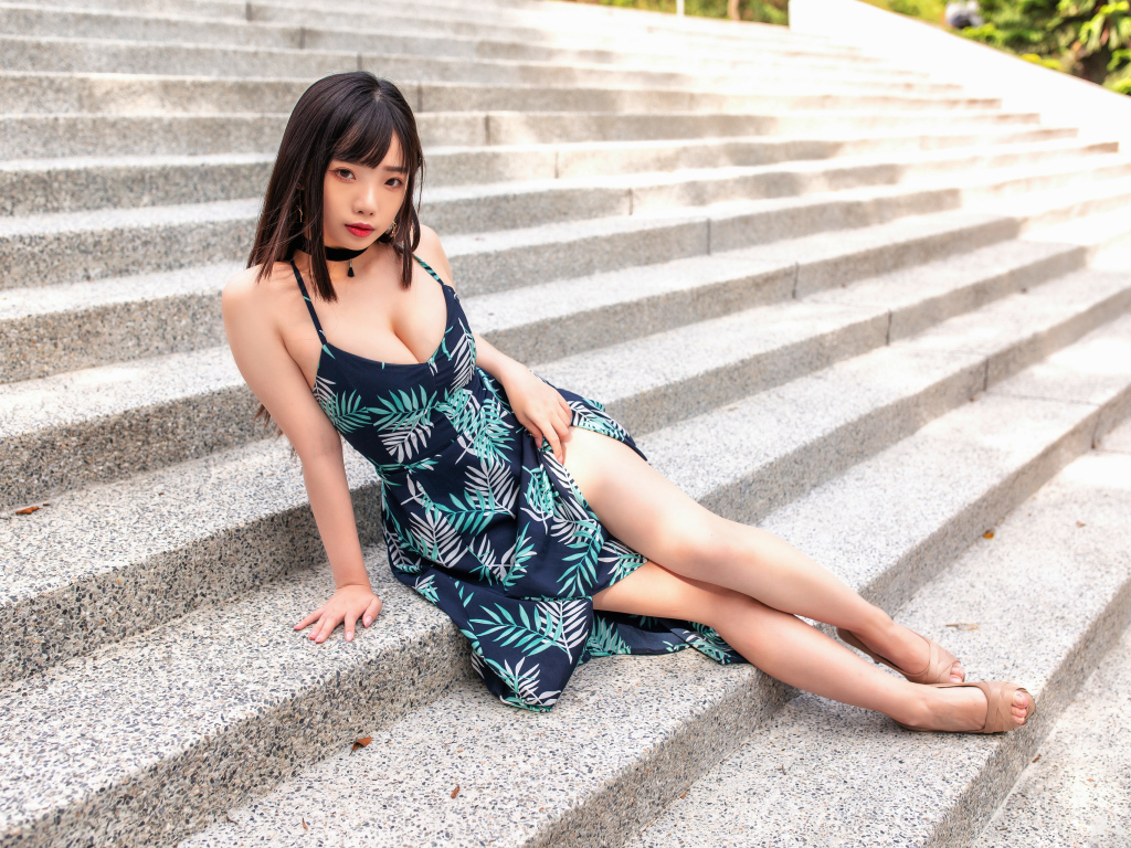 Девушка азиатка в платье сидит на ступеньках