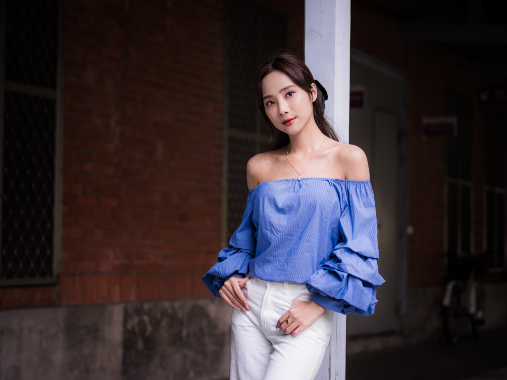 Девушка азиатка в белых брюках у дома