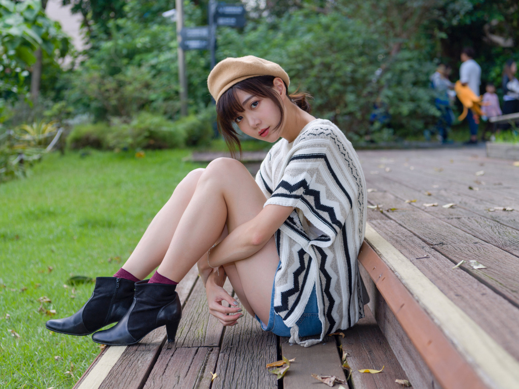 Девушка азиатка сидит в парке на лавке 