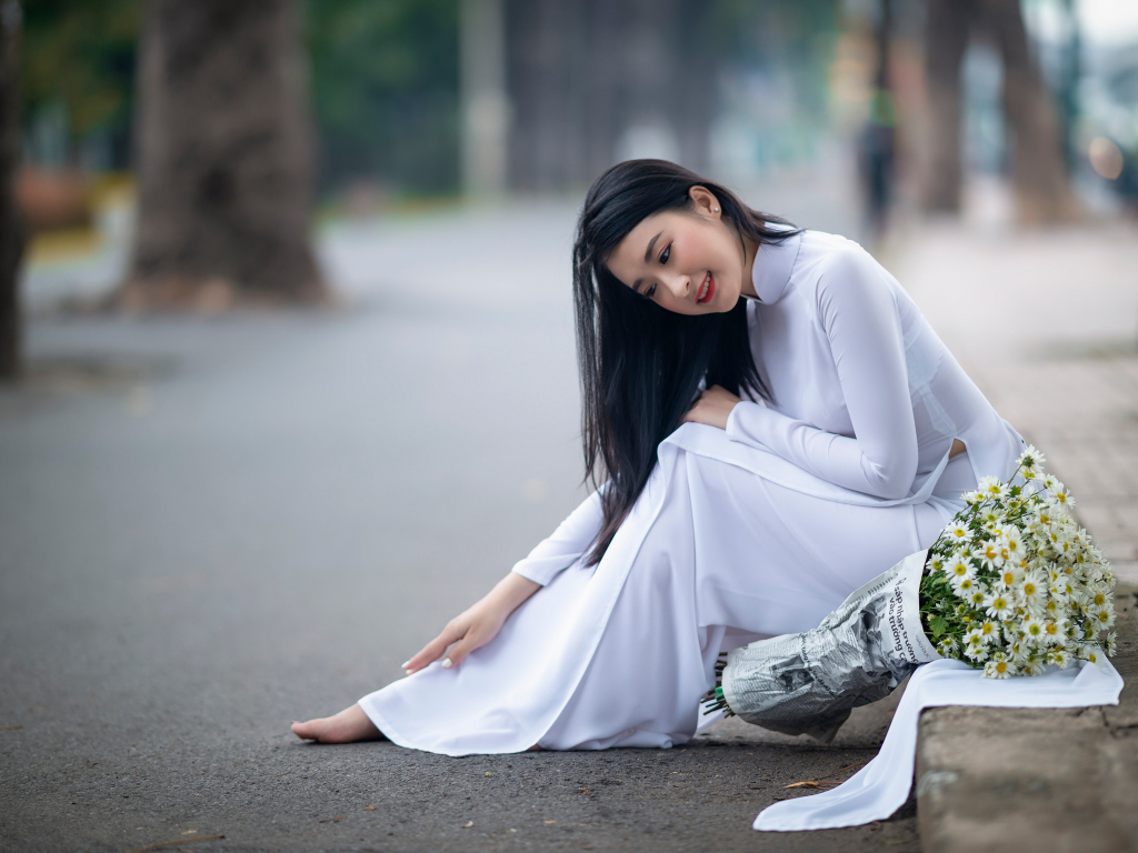Красивая девушка азиатка в белом платье с букетом ромашек
