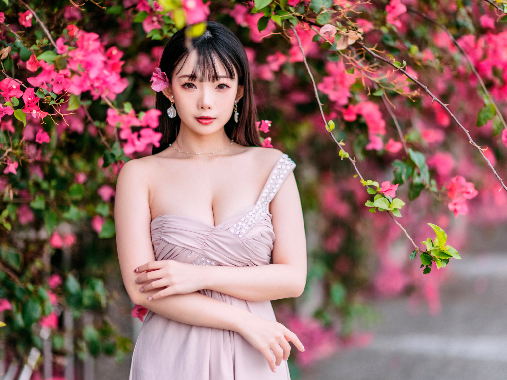 Красивая девушка азиатка у куста с  красными цветами 