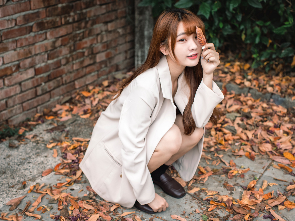 Красивая девушка азиатка на земле с опавшей листвой 