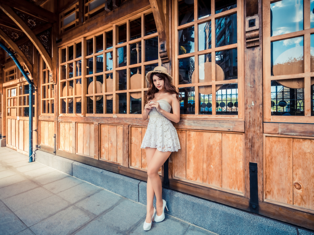 Красивая девушка азиатка стоит у стены с большими окнами