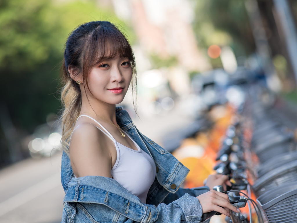 Красивая азиатка в джинсовой куртке с велосипедом