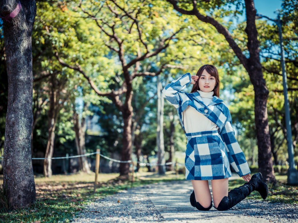 Красивая девушка азиатка стоит на коленях в парке