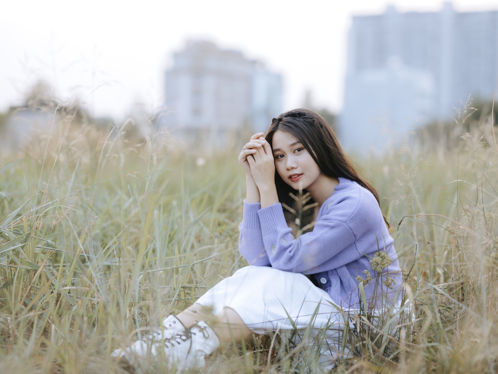 Красивая девушка азиатка сидит на поле с травой 