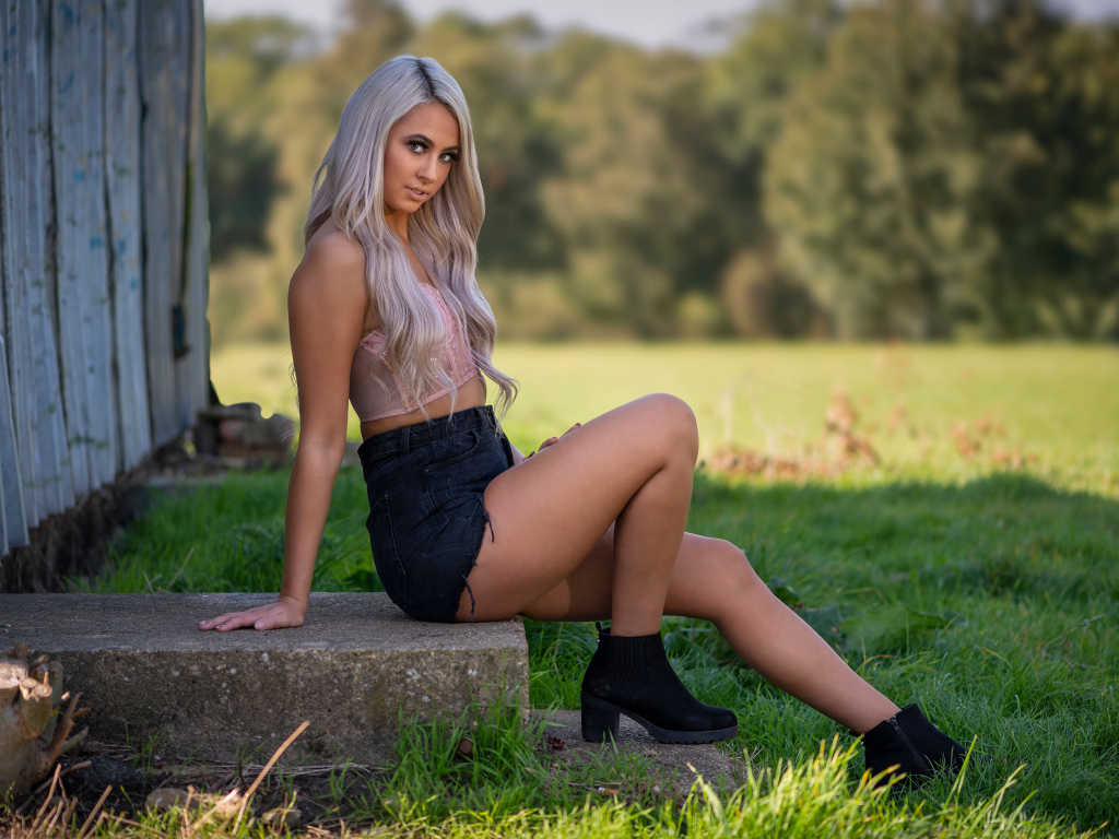 Красивая блондинка в черных шортах сидит на ступеньках 