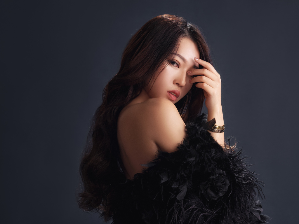 Красивая девушка в черном манто на сером фоне